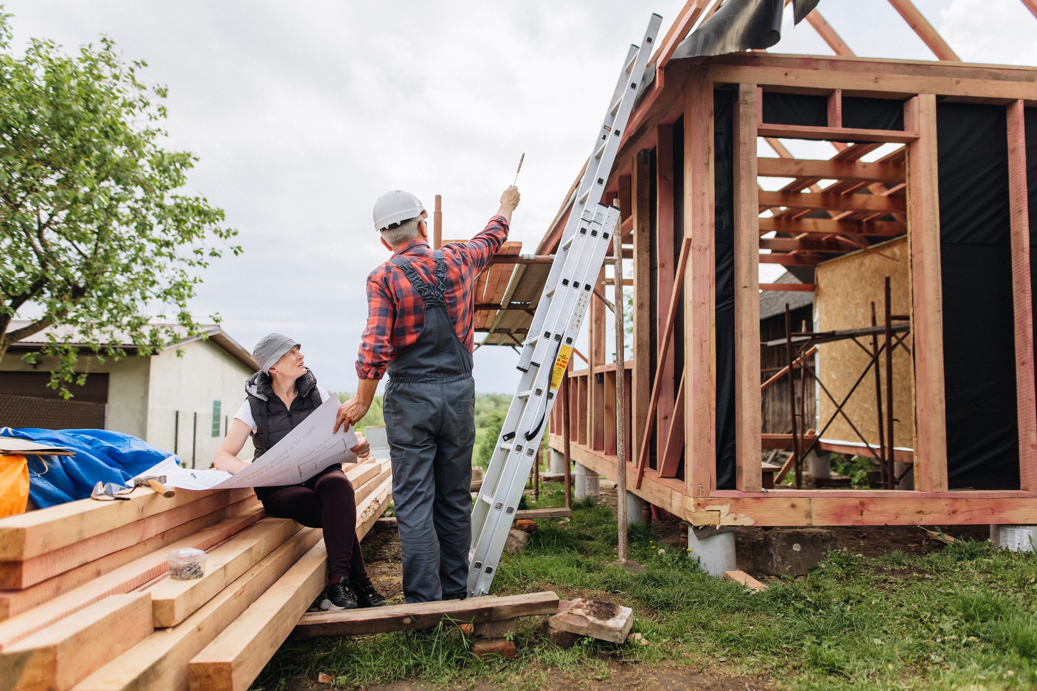 Workers examining blueprints near a house frame